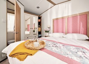 Een slaapkamer met een bed, nachtkastje, spiegel, kledingkast en raam.