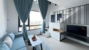 Una sala de estar moderna con sofá, una mesa de centro, televisor y una escalera que lleva a un nivel superior.