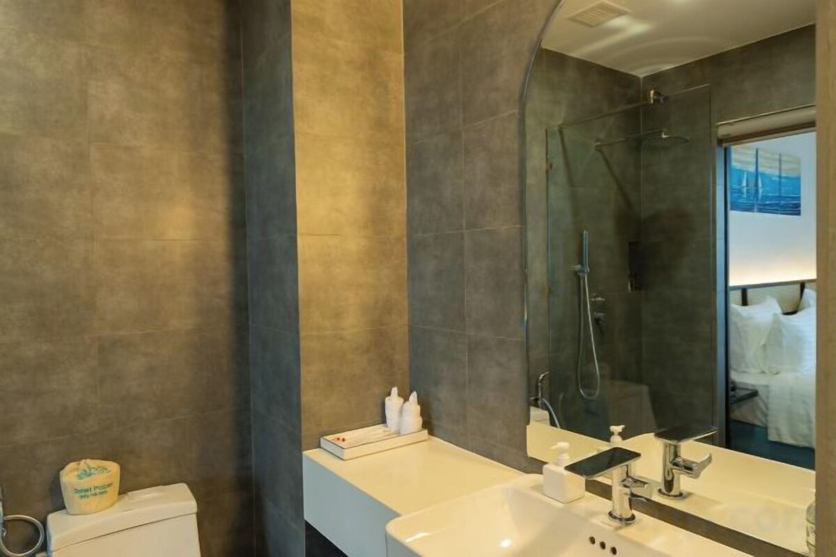 A bathroom with a toilet, sink, mirror, and shower.