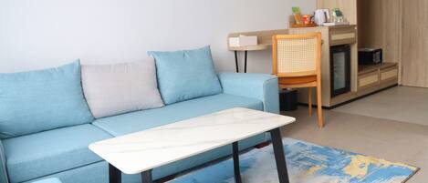 Una sala de estar moderna con un sofá azul claro, una mesa de centro blanca y una silla de mimbre.