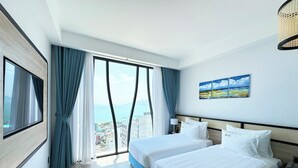 Habitación de hotel con dos camas, televisión, un cuadro y vistas a la ciudad.