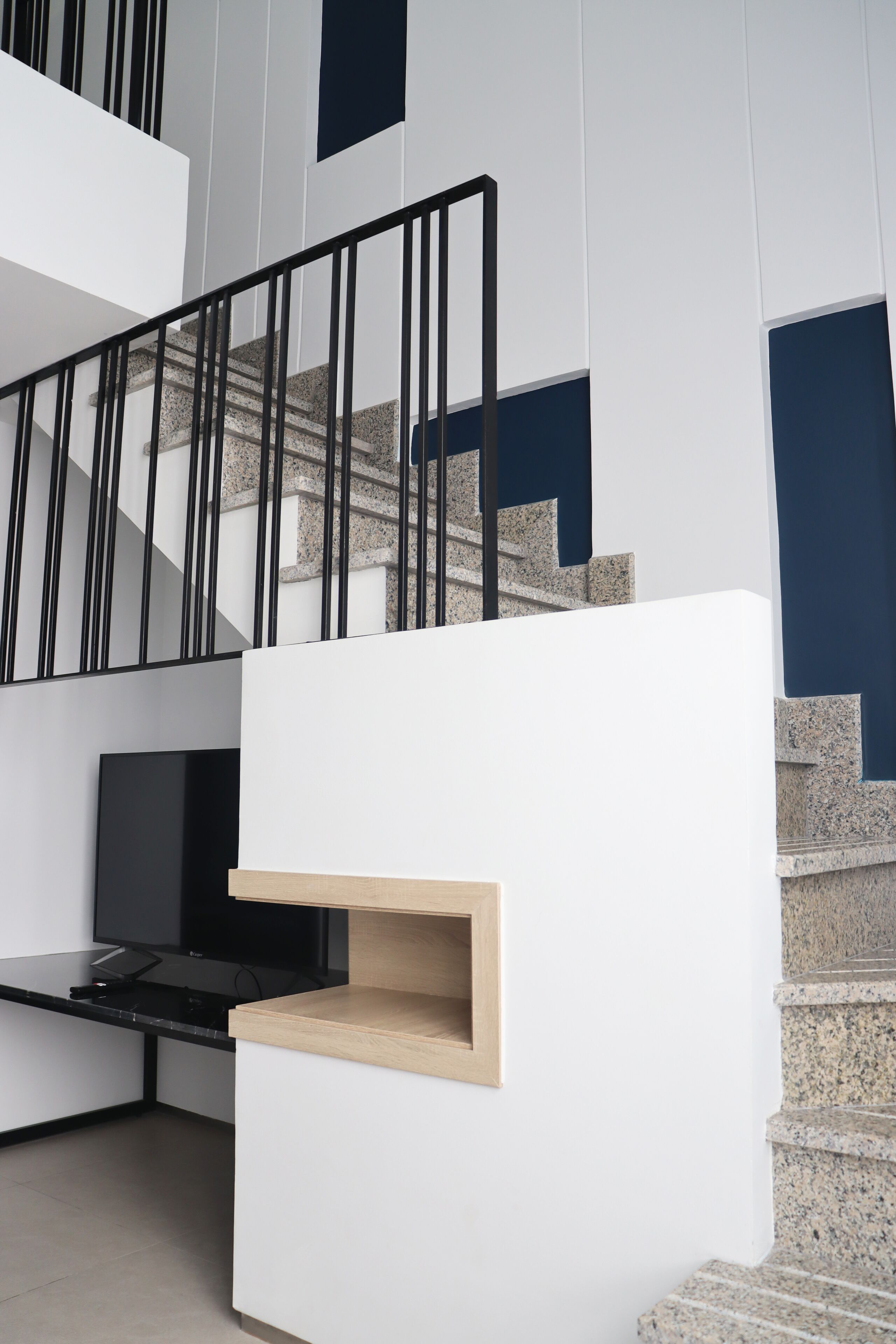 Ein modernes Interieur mit Treppe, Flachbildfernseher und einer Holzkammer.