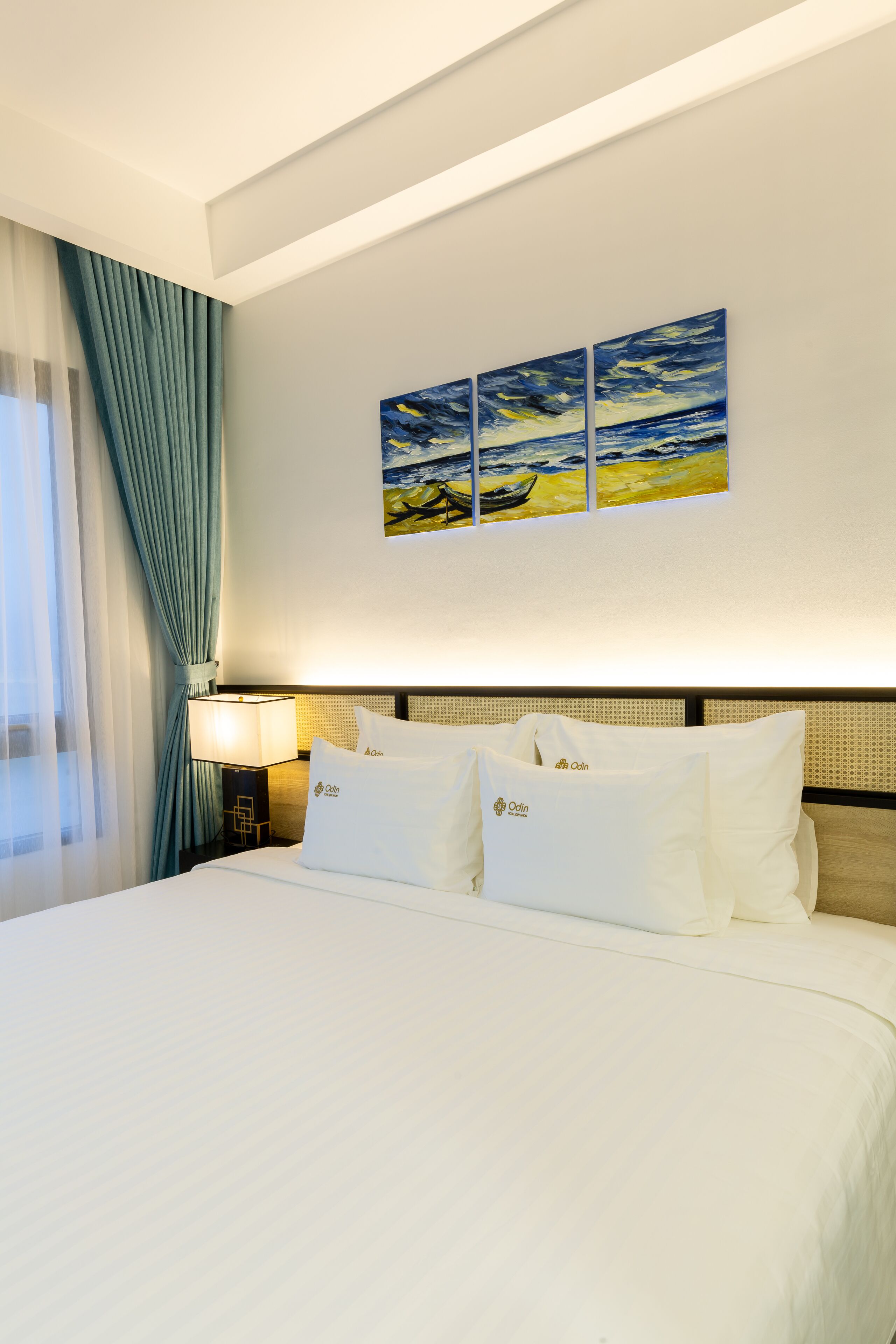A hotel room with a large bed, a nightstand with a lamp, and a painting on the wall.