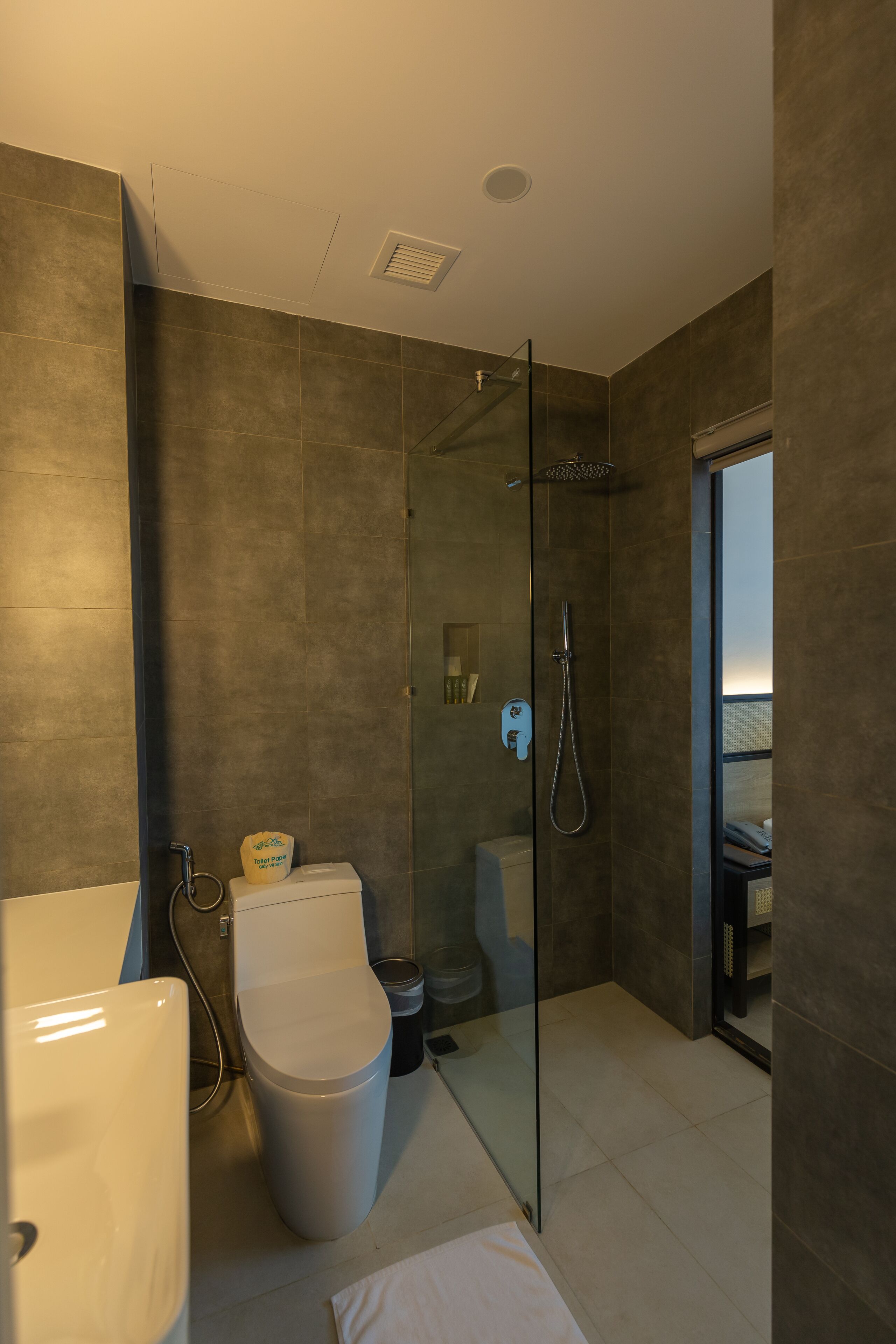 A modern bathroom with a glass-enclosed shower, a toilet, and a sink.
