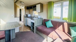 Un espacio habitable compacto con kitchenette, un sofá y una mesa de comedor.