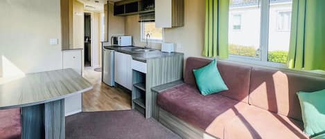Un espacio habitable compacto con kitchenette, un sofá y una mesa de comedor.