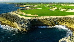 Un parcours de golf situé sur la côte, avec des bunkers et un plan d’eau.