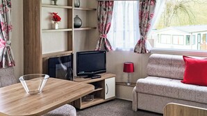 A cozy room with a wooden table, a sofa, a TV, and a lamp. - 3 bedroom accommodation in Buxton (Buxton)