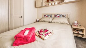 A bedroom with a bed, a wardrobe, a shelf with decorative items, and a bedside table with a book and a tissue box. - 3 bedroom accommodation in Buxton (Buxton)