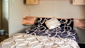 A bed with a patterned bedspread, a single pillow, and wooden headboard shelves. - 3 bedroom accommodation in Buxton (Buxton)