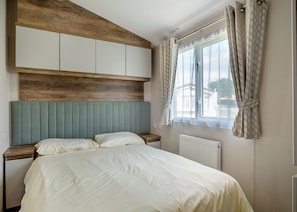 Une chambre à coucher avec une tête de lit en bois, un lit avec une literie blanche, une table de chevet et une fenêtre avec des rideaux.