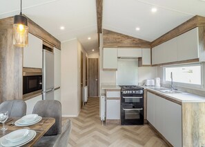 A modern kitchen with a built-in oven, a microwave, and a dining area with a table set for two.