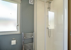 Une salle de bain avec une douche, des toilettes, un porte-serviettes et une fenêtre.