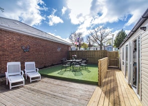 A backyard with a patio, a brick wall, a wooden deck, and a fenced area. - Oak 3 Hot Tub + Private Garden (Axminster)