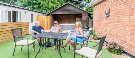 A patio with a table and chairs, a wooden fence, and a brick wall with a decorative element.