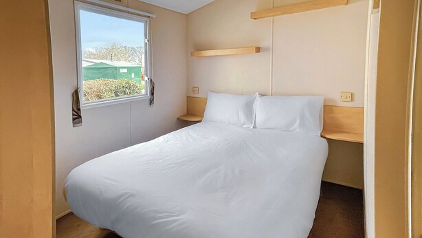 A small, single-bed room with a window, a bedside table, and a wall-mounted shelf. - 3 bedroom accommodation in Newbridge, Nr Yarmouth (Newbridge, Nr Yarmouth)