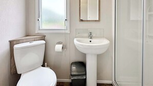 Un baño con inodoro, lavabo, espejo y ventana.