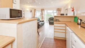 A compact kitchen with a microwave, a washing machine, and a coffee maker. - Bungalow with one double and one twin. (Trearddur Bay, Holyhead)