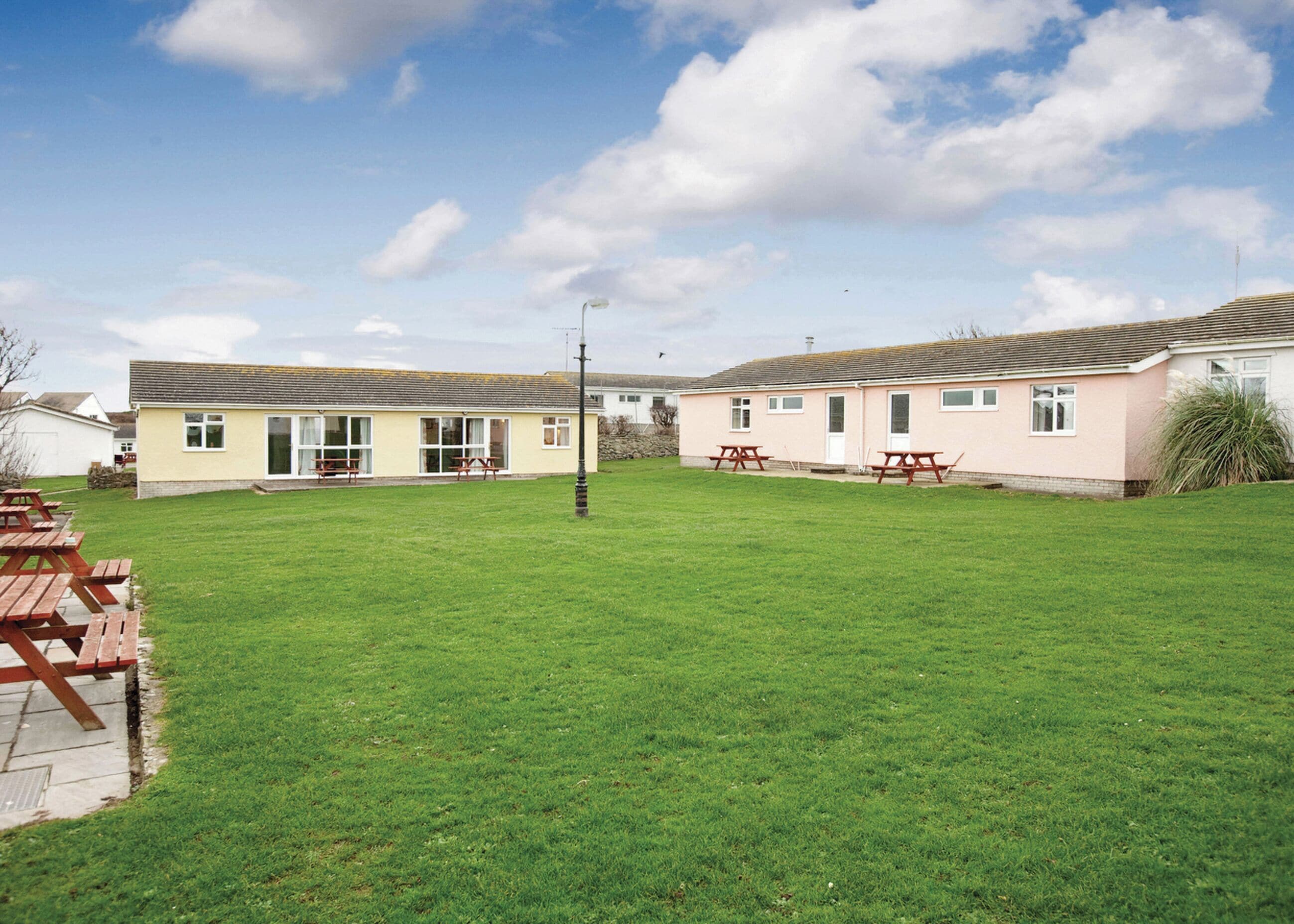 A two-story building with a flat roof, a grassy yard, and picnic tables.