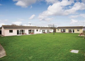 A row of single-story buildings with picnic tables in the yard. - Bungalow with one double and one twin. (Trearddur Bay, Holyhead)