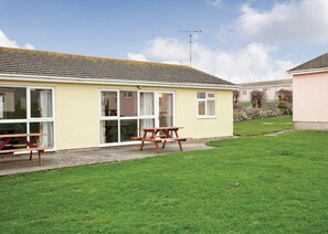 A yellow building with large windows and a picnic table in the yard. - Bungalow with one double and one twin. (Trearddur Bay, Holyhead)