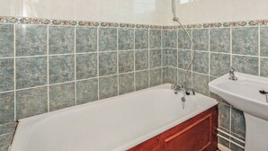 A bathroom with a bathtub, a sink, and a shower. - Bungalow with one double and one twin. (Trearddur Bay, Holyhead)