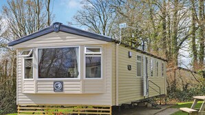 Une maison mobile dotée d’un porche à l’avant, d’une petite dépendance attenante et d’une table de pique-nique.