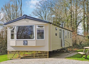A mobile home with a front porch, a small attached structure, and a picnic table.