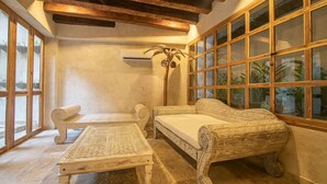 A room with a wooden ceiling, a sofa, a table, and large windows with plants. - 5 Bedroom Luxury Villa in Old City (Cartagena)