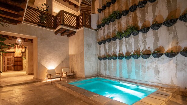 A pool area with a stone floor, a wooden bench, and a wall decorated with hanging planters. - 5 Bedroom Luxury Villa in Old City (Cartagena)