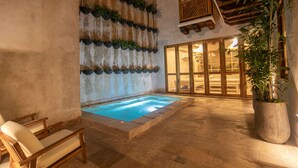 A pool area with a wooden deck, lounge chairs, and a potted plant. - 5 Bedroom Luxury Villa in Old City (Cartagena)