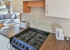 A compact kitchen with a gas stove, a coffee maker, and a toaster.