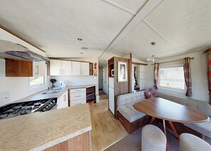 A compact RV interior with a kitchenette, a dining area, and a seating space. - Well presented 12ft-wide caravan with one double and one twin. (Clunderwen, Nr Narberth)
