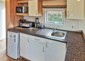 A compact kitchenette with a sink, a microwave, a toaster, and a small refrigerator.