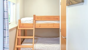 A bunk bed with a ladder, white bedding, a window with curtains, and a door. - 1 bedroom accommodation in Silloth (Silloth)