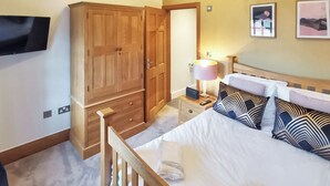Una camera da letto con un letto di legno, comodini, una lampada e una TV montata a parete.