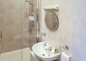 Ein Badezimmer mit Dusche, Waschbecken und Spiegel.