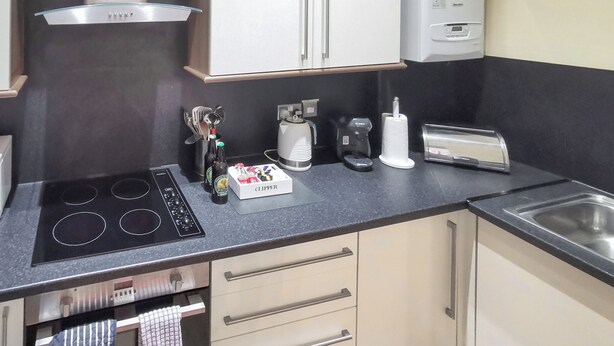 Una cucina compatta con un fornello, una moka, un tostapane e una scatola con l'etichetta 'CLIPPER'.