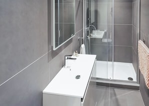 A modern bathroom with a glass shower enclosure, a white sink, and a mirror. - Carmarthenshire Cottage (Clunderwen, Nr Narberth)