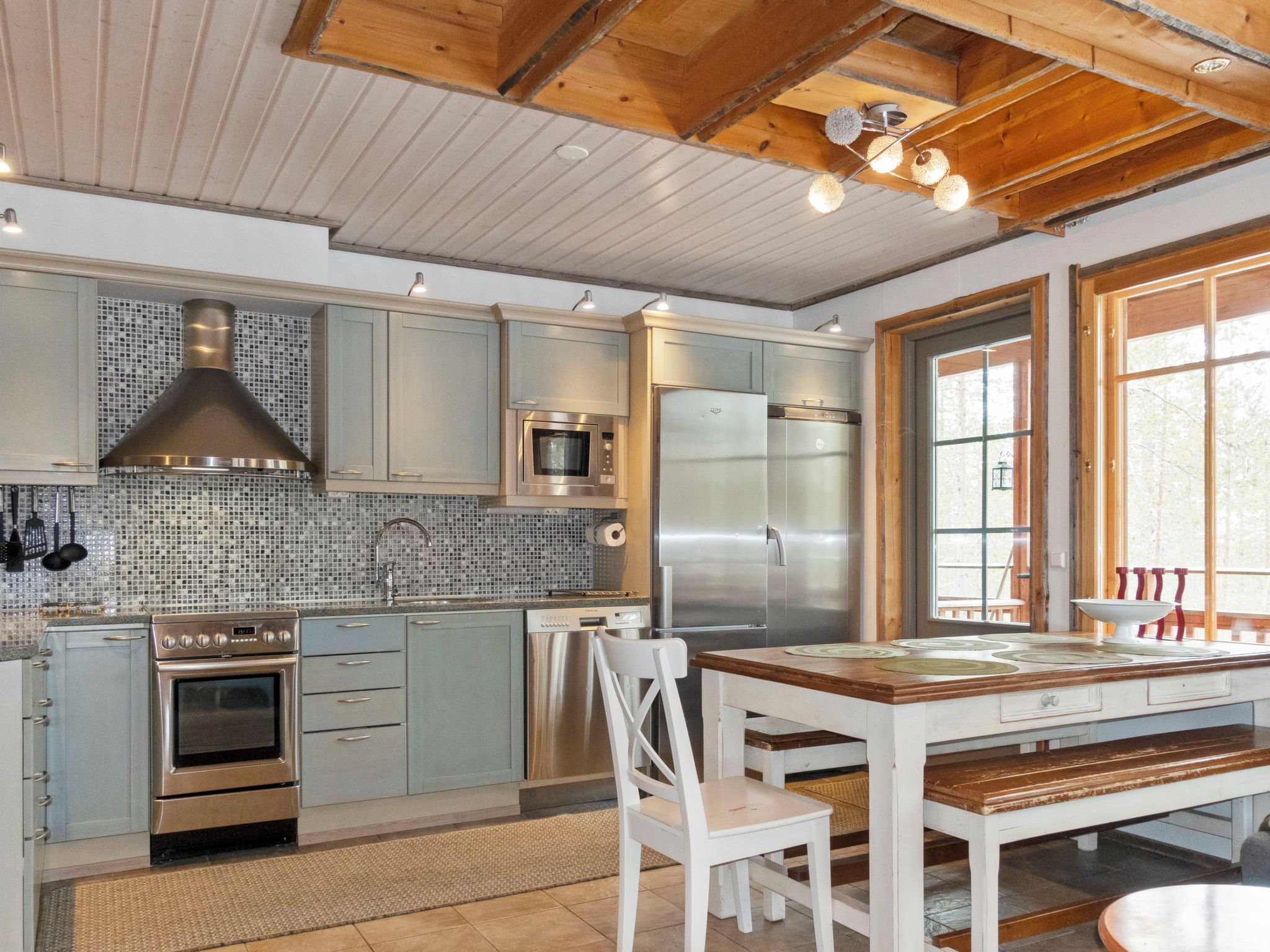 A modern kitchen with stainless steel appliances, a tiled backsplash, and wooden ceiling beams.