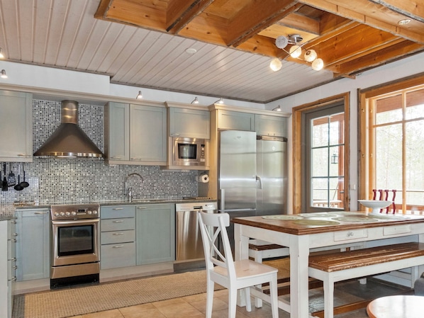 A modern kitchen with stainless steel appliances, a tiled backsplash, and wooden ceiling beams.