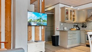 Une cuisine moderne avec des meubles de couleur bleu clair, un pare-feu en carrelage et un téléviseur à écran plat fixé sur un mur en bois.