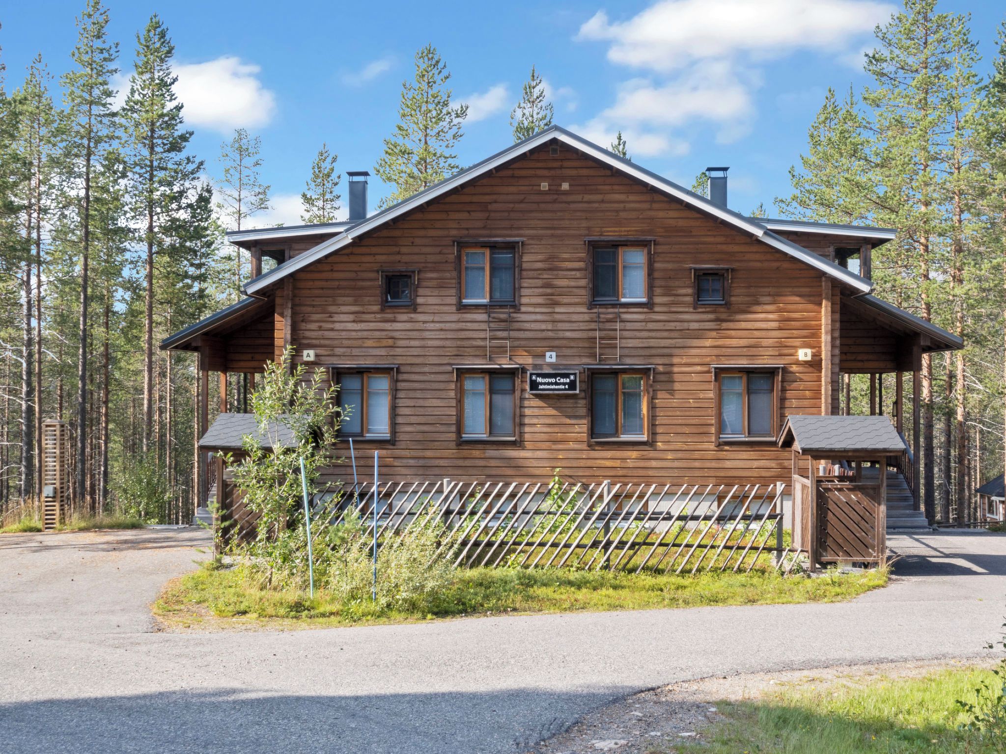 A wooden cabin with a sign indicating it is a new house, surrounded by a forest.