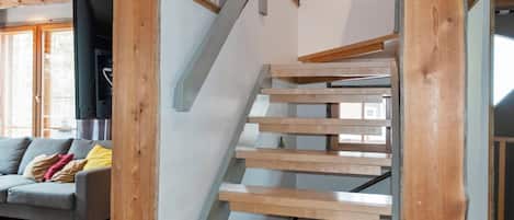 Un intérieur moderne avec un escalier en bois, un canapé gris et un téléviseur à écran plat.