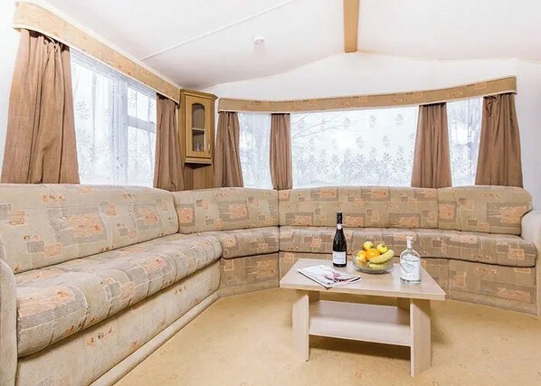 A corner sofa with a table, a bottle, and fruit.