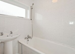 Une salle de bain avec une baignoire, un lavabo et une fenêtre.