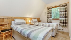 A room with two beds, a wooden bench, a nightstand with a lamp, and a window with curtains. - Highland Ranch Lodge (Delny, Nr Invergordon)