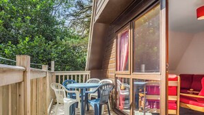 A wooden deck with a table and chairs, a red couch, and a glass door leading to a room. - Highland Ranch Lodge (Delny, Nr Invergordon)