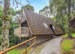 A house with a sloped roof, a balcony, and a gravel driveway.