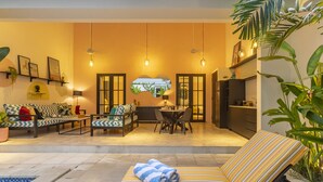 A cozy living area with a sofa, dining table, and chairs. There is a small pool and a lounge chair with a towel. - Villa Caorrun (Canggu)